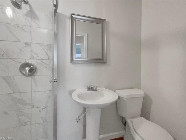 bathroom with a tile shower and toilet