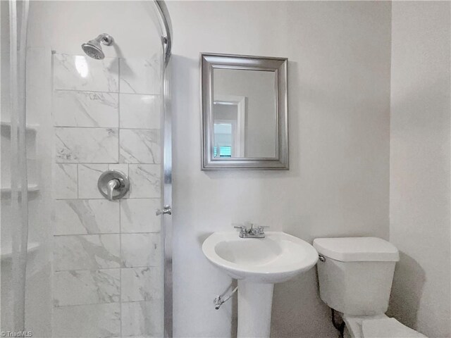 bathroom featuring tiled shower and toilet