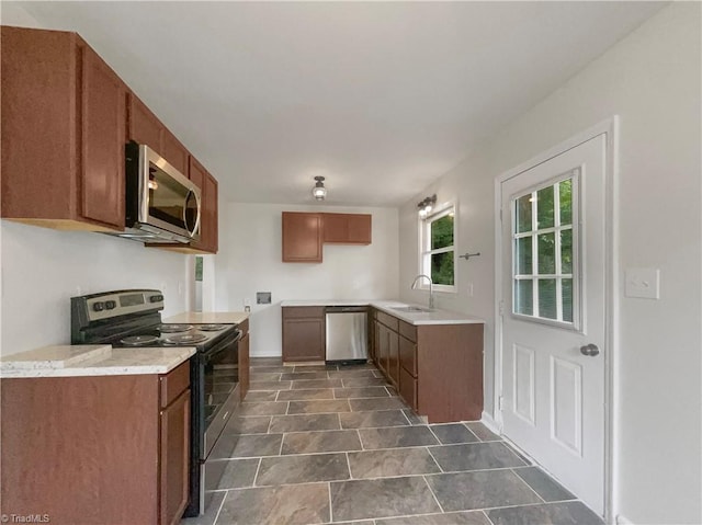 kitchen with sink, appliances with stainless steel finishes, and dark tile patterned floors