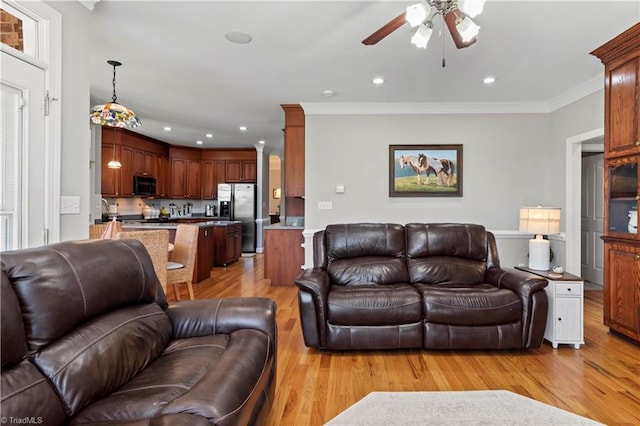 living area with recessed lighting, light wood-type flooring, a ceiling fan, and crown molding