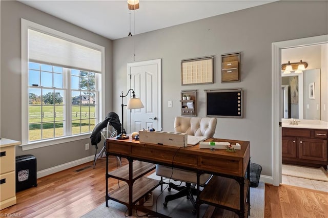 office space featuring light wood-type flooring, a sink, and baseboards