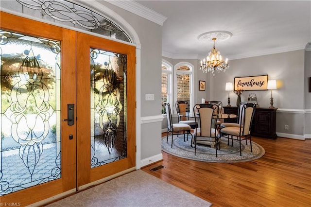 foyer with crown molding, french doors, visible vents, and an inviting chandelier