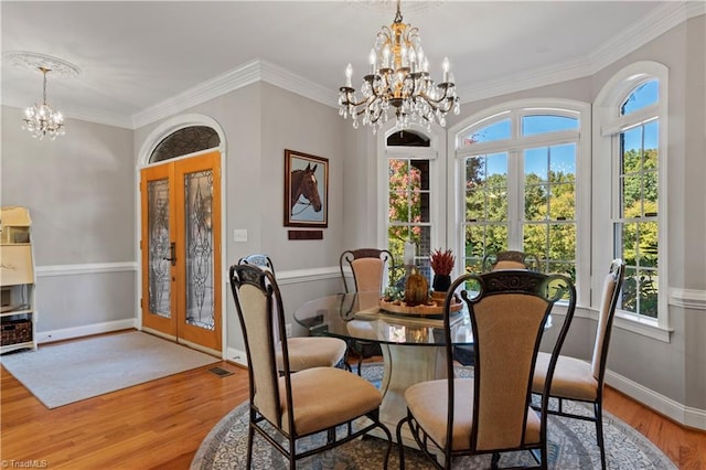 dining area featuring ornamental molding, wood finished floors, french doors, and an inviting chandelier