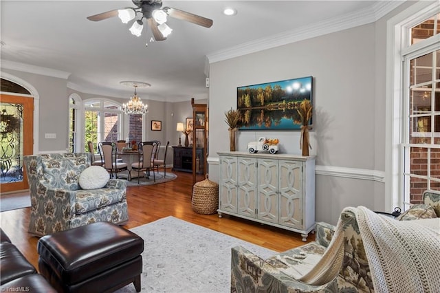 living room featuring ornamental molding, wood finished floors, and ceiling fan with notable chandelier