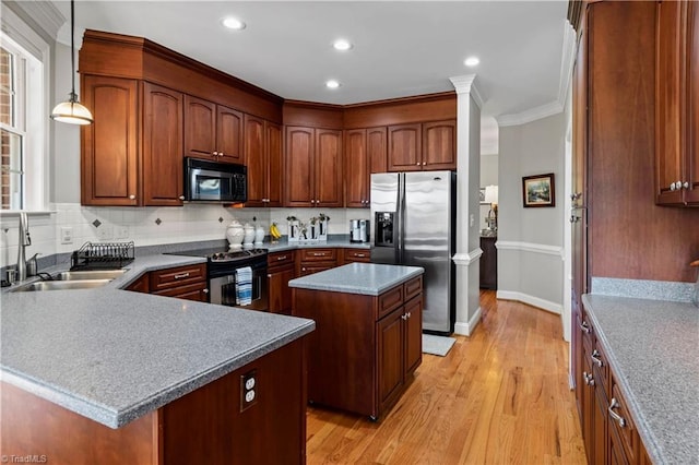 kitchen featuring light wood finished floors, backsplash, appliances with stainless steel finishes, a sink, and a kitchen island