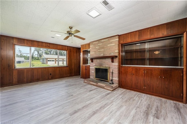 8521 US Highway 64 E, Ramseur, NC 27316 - unfurnished living room featuring wood walls, a ceiling fan, light wood-style flooring, and a brick fireplace