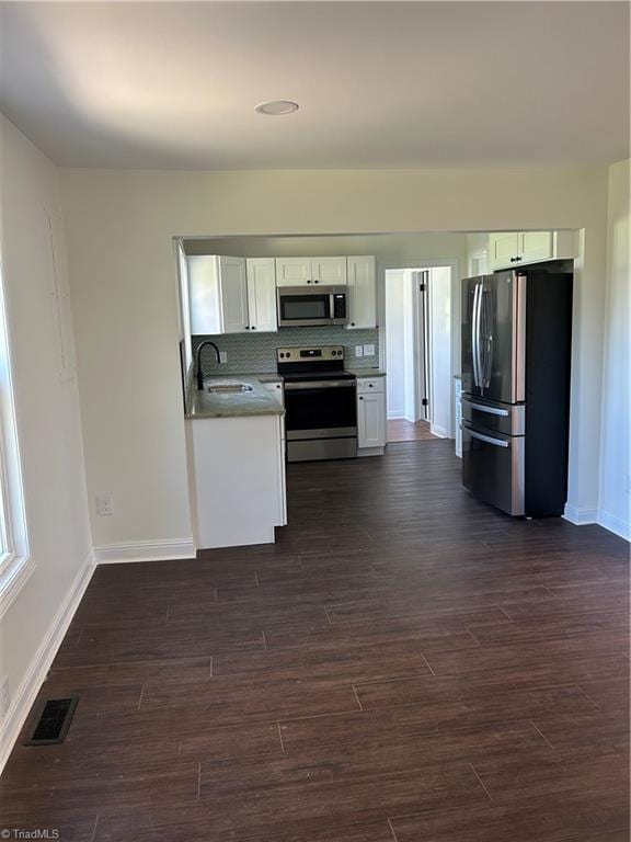 kitchen with visible vents, white cabinets, a sink, dark wood finished floors, and stainless steel appliances