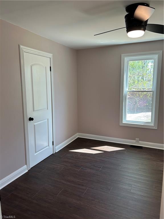unfurnished room with dark wood-type flooring and baseboards