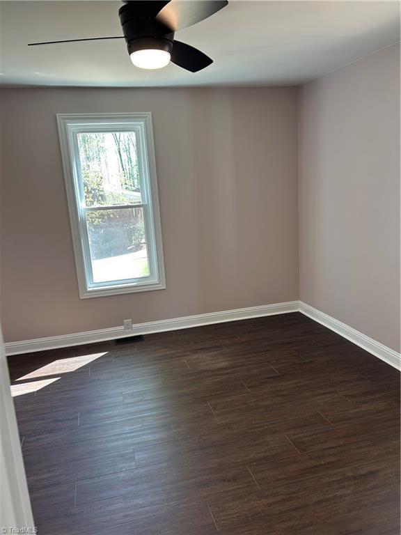unfurnished room with dark wood-style flooring, baseboards, and a ceiling fan