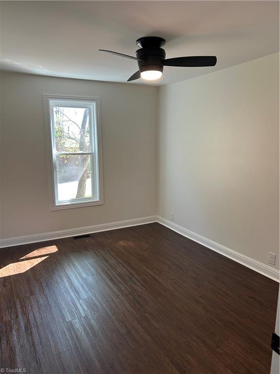 unfurnished room with dark wood-style floors, baseboards, and a ceiling fan