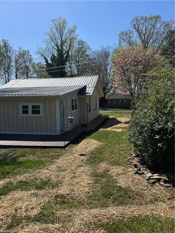 view of side of property with board and batten siding, metal roof, and a yard