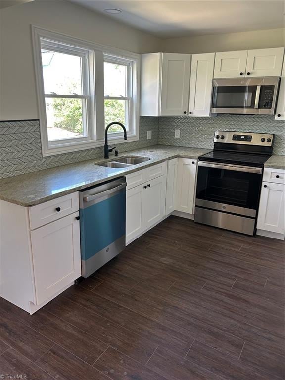 kitchen featuring dark wood-type flooring, appliances with stainless steel finishes, a sink, and white cabinetry