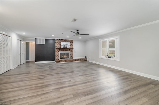 unfurnished living room with ornamental molding, light wood-type flooring, ceiling fan, and a fireplace