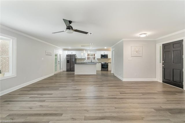 unfurnished living room with light wood-type flooring, ornamental molding, sink, and ceiling fan