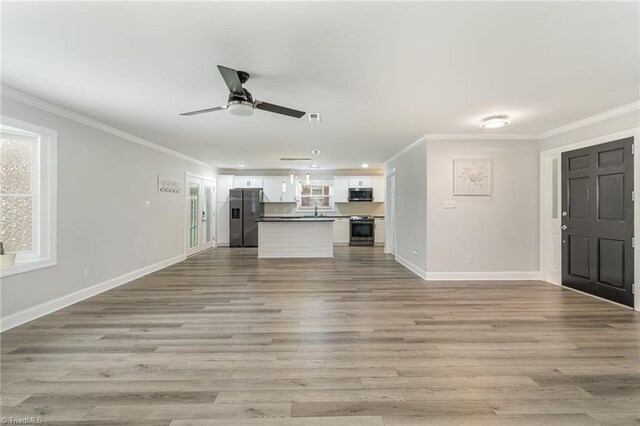 kitchen with light wood-type flooring, sink, white cabinetry, appliances with stainless steel finishes, and decorative light fixtures