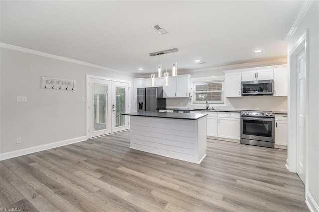 kitchen with light hardwood / wood-style floors, white cabinetry, pendant lighting, and stainless steel appliances