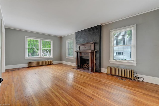 unfurnished living room with radiator, light hardwood / wood-style flooring, and a wealth of natural light