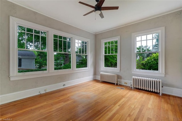 spare room with radiator heating unit, light wood-type flooring, ceiling fan, and ornamental molding