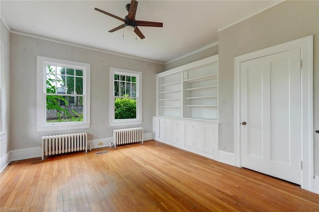 unfurnished room featuring ceiling fan, radiator, light wood-type flooring, and crown molding