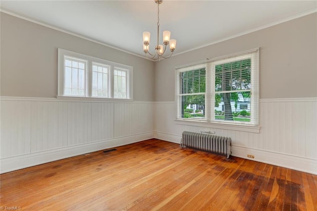 unfurnished room featuring a healthy amount of sunlight, radiator heating unit, and hardwood / wood-style flooring