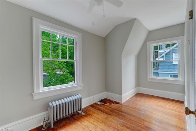 bonus room featuring radiator, light hardwood / wood-style flooring, lofted ceiling, and a healthy amount of sunlight