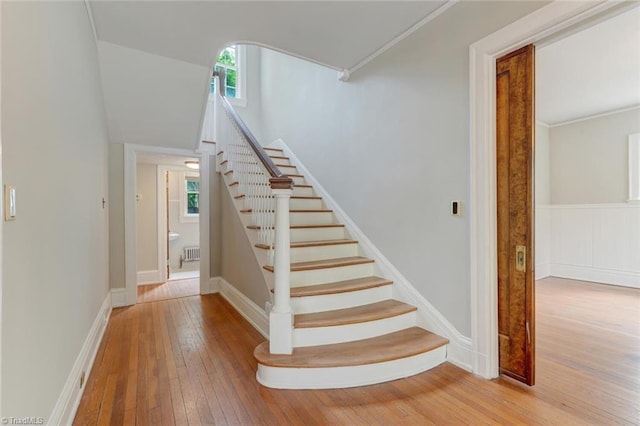 stairs featuring ornamental molding, plenty of natural light, and hardwood / wood-style floors