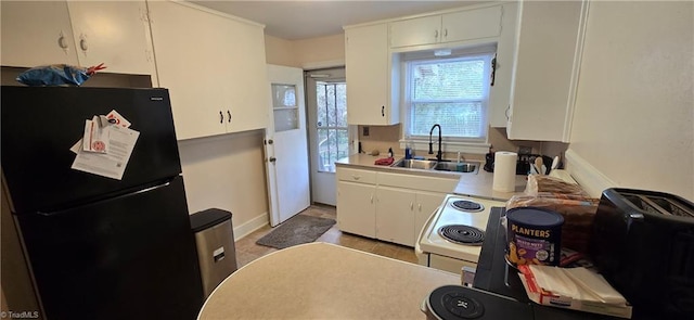 kitchen featuring freestanding refrigerator, a sink, light countertops, white cabinetry, and white range with electric stovetop