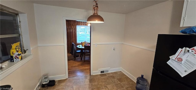 interior space featuring decorative light fixtures, visible vents, freestanding refrigerator, and baseboards