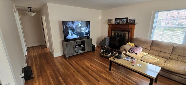 living room featuring a glass covered fireplace, wood finished floors, and baseboards