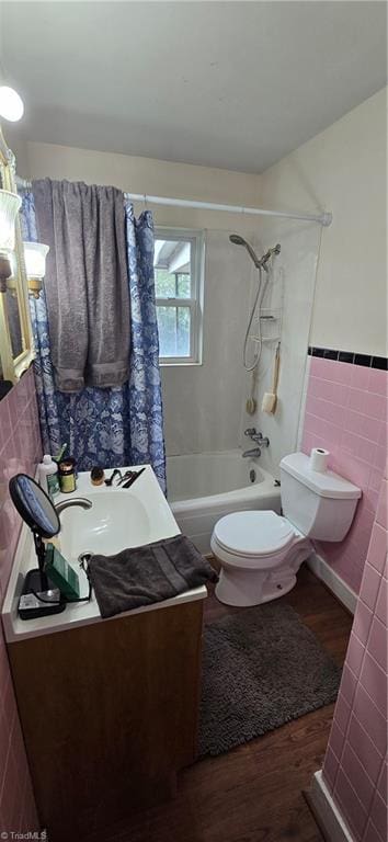 bathroom with toilet, wood finished floors, tile walls, shower / bath combination, and vanity