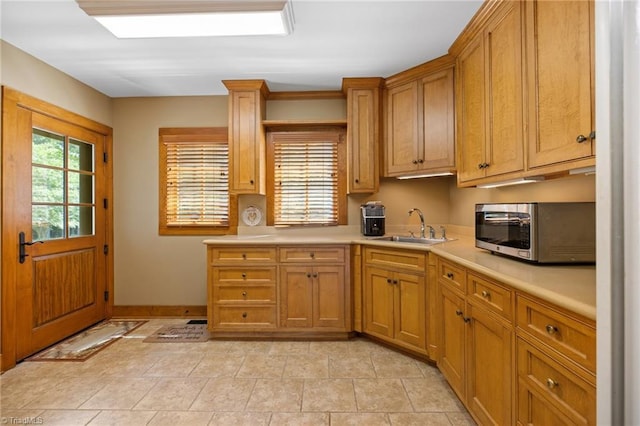 7239 Bulb Rd, Julian, NC 27283 - kitchen with stainless steel microwave, light countertops, light tile patterned floors, and brown cabinets