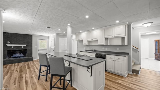 1926 Downing Dr, Burlington, NC 27215 - kitchen featuring black appliances, dark countertops, light wood-style floors, white cabinets, and a kitchen bar