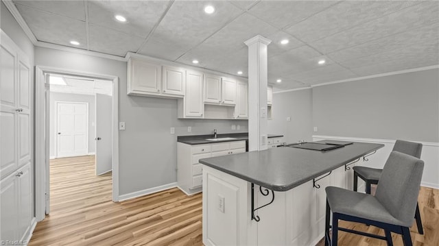 1926 Downing Dr, Burlington, NC 27215 - kitchen with dark countertops, light wood-style floors, white cabinetry, a breakfast bar area, and recessed lighting