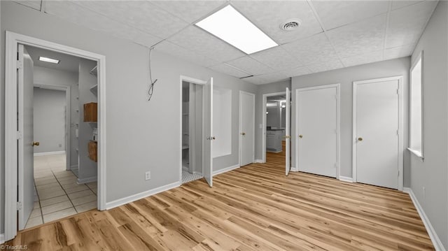 1926 Downing Dr, Burlington, NC 27215 - unfurnished bedroom with light wood-style flooring, multiple closets, a paneled ceiling, and connected bathroom