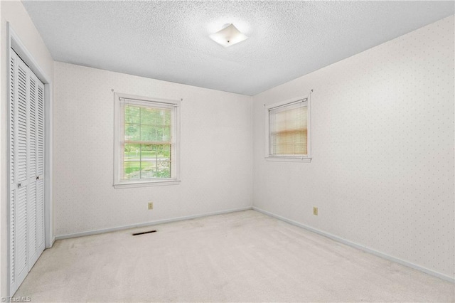 3228 Valley Rd, Winston-Salem, NC 27106 - unfurnished bedroom featuring carpet, a closet, a textured ceiling, and wallpapered walls