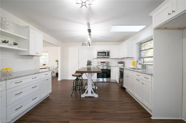 kitchen featuring appliances with stainless steel finishes, light stone counters, dark hardwood / wood-style flooring, and white cabinets