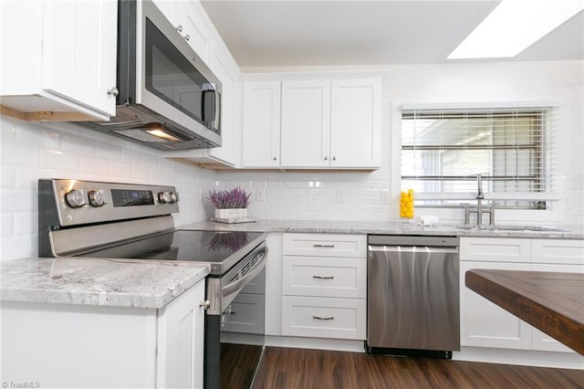 kitchen with white cabinets, tasteful backsplash, dark wood-type flooring, appliances with stainless steel finishes, and light stone countertops