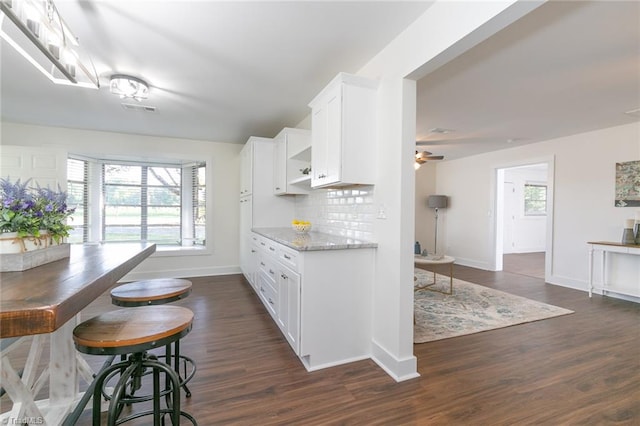 kitchen featuring ceiling fan, tasteful backsplash, white cabinetry, light stone countertops, and dark hardwood / wood-style flooring