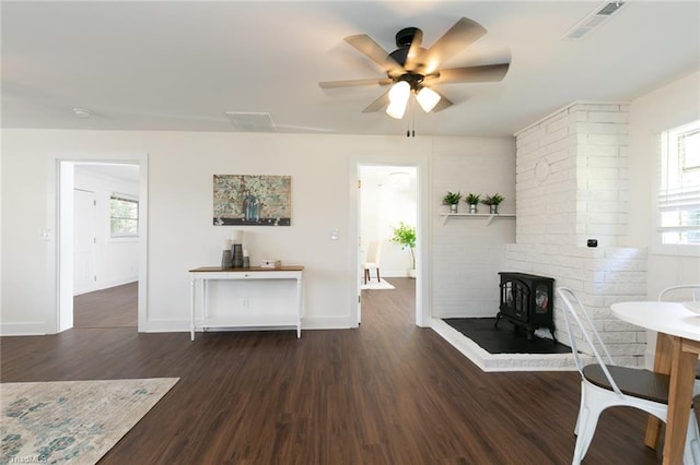 dining room featuring ceiling fan, dark hardwood / wood-style floors, and a wood stove