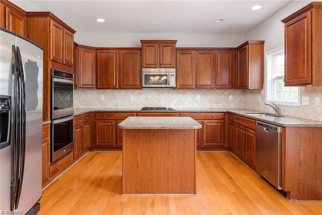 3704 Worthing Ct, Greensboro, NC 27455 - kitchen featuring stainless steel appliances, a sink, light wood-style flooring, a center island, and light stone countertops