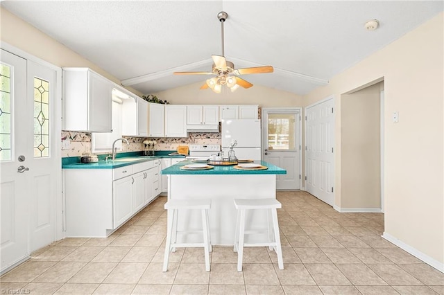 kitchen with white cabinetry, lofted ceiling, sink, backsplash, and white appliances