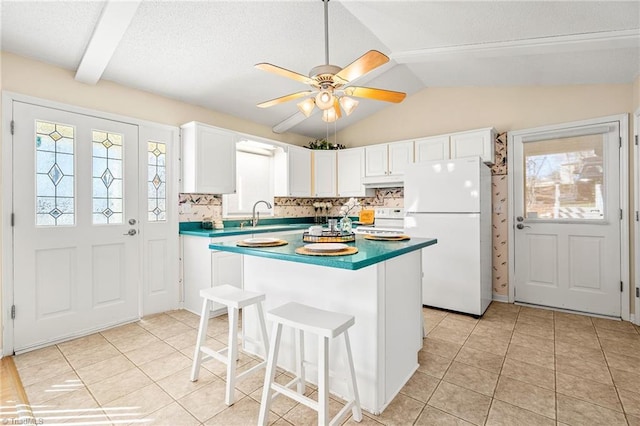 kitchen featuring lofted ceiling, white appliances, backsplash, a center island, and white cabinets