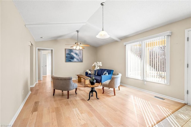 sitting room with ceiling fan, vaulted ceiling, and light wood-type flooring