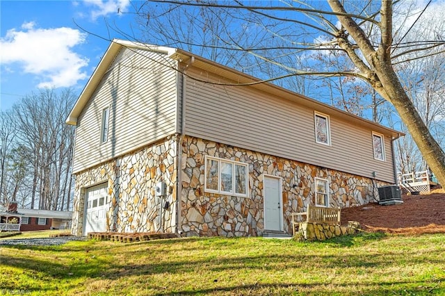 back of property with a garage, a yard, and central air condition unit