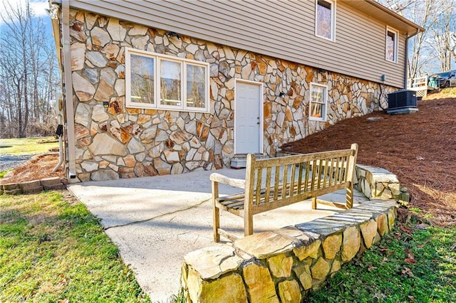 view of exterior entry featuring central AC and a patio