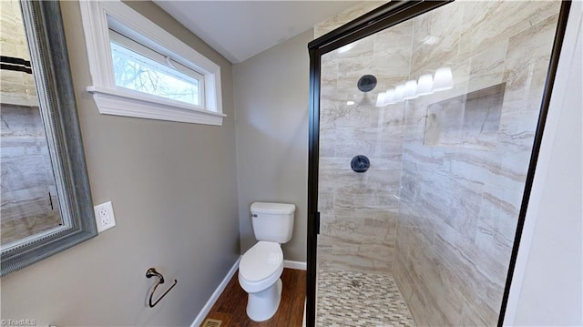 bathroom with hardwood / wood-style flooring, toilet, and a shower with shower door