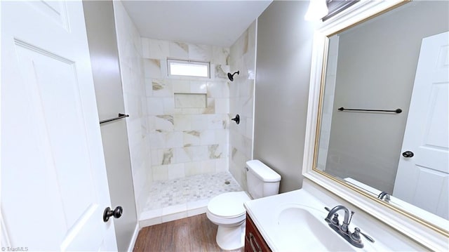 bathroom featuring hardwood / wood-style flooring, vanity, toilet, and tiled shower