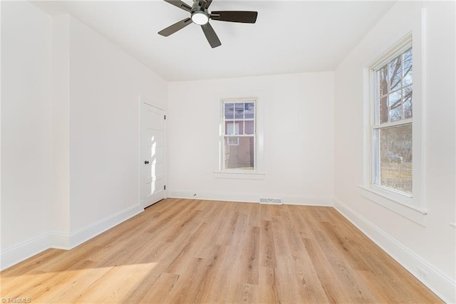 empty room with visible vents, ceiling fan, light wood-style flooring, and baseboards