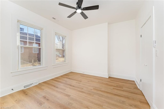 empty room with light wood-style flooring, visible vents, and baseboards