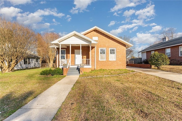 bungalow-style house featuring a porch, a front yard, brick siding, and fence